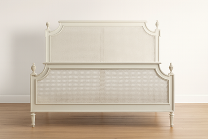 White bed with caned headboard on a wooden floor