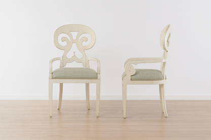 Two white chairs with decorative backrests on a wooden floor.